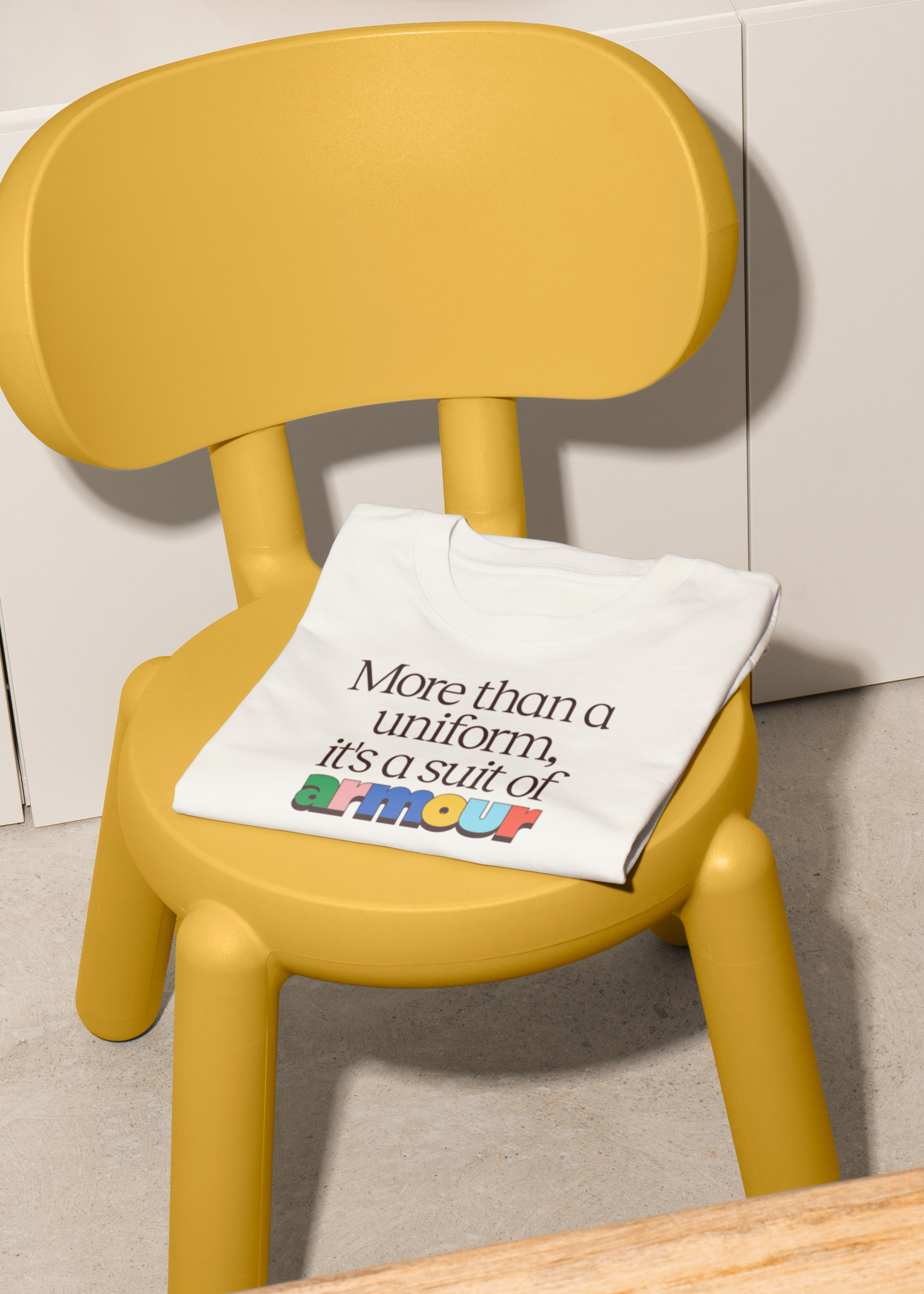 Branded t-shirt draped over a plastic yellow children's chair.