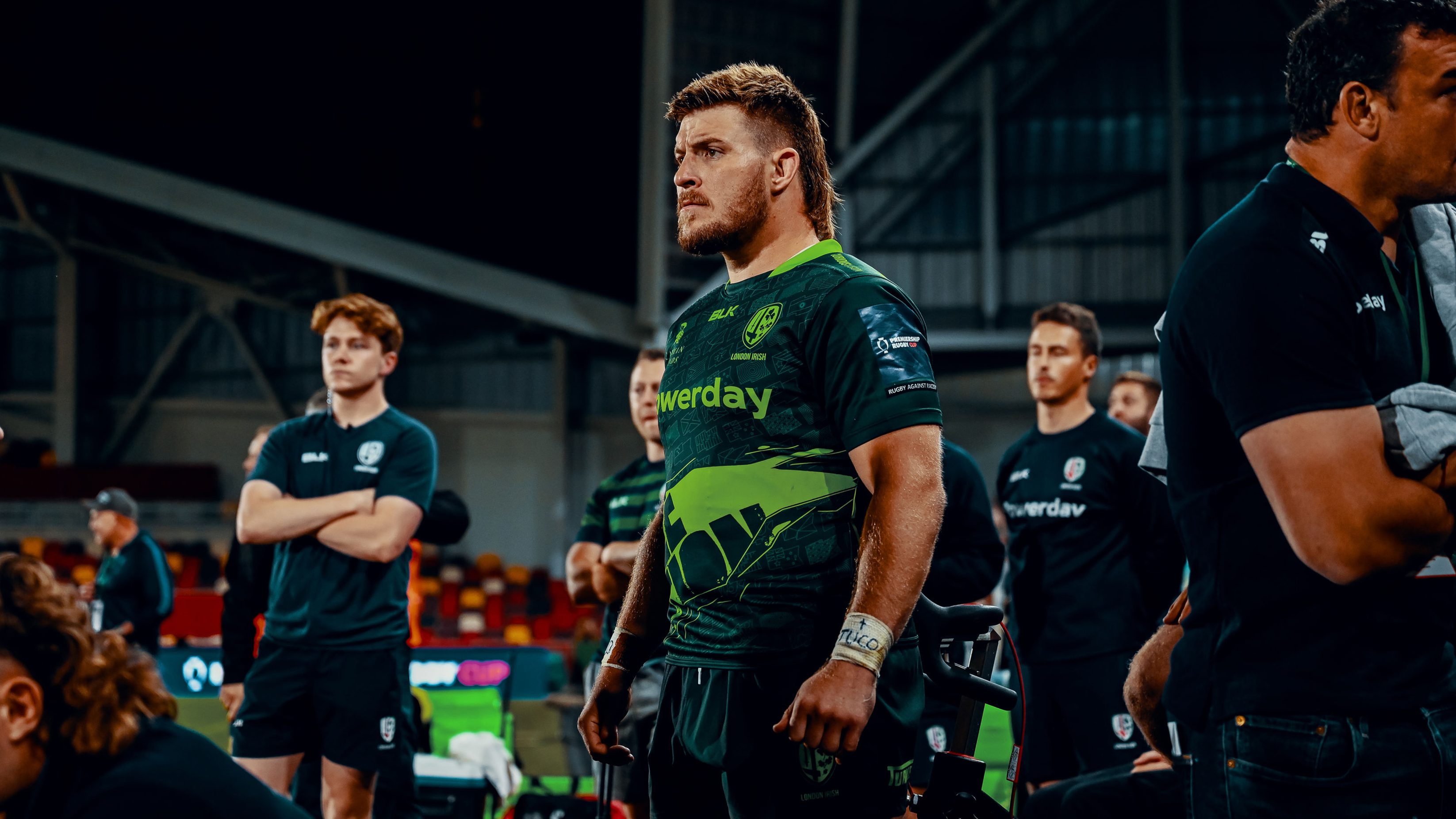A London Irish player watching on the sidelines of the pitch, wearing the 2022 Euro Kit