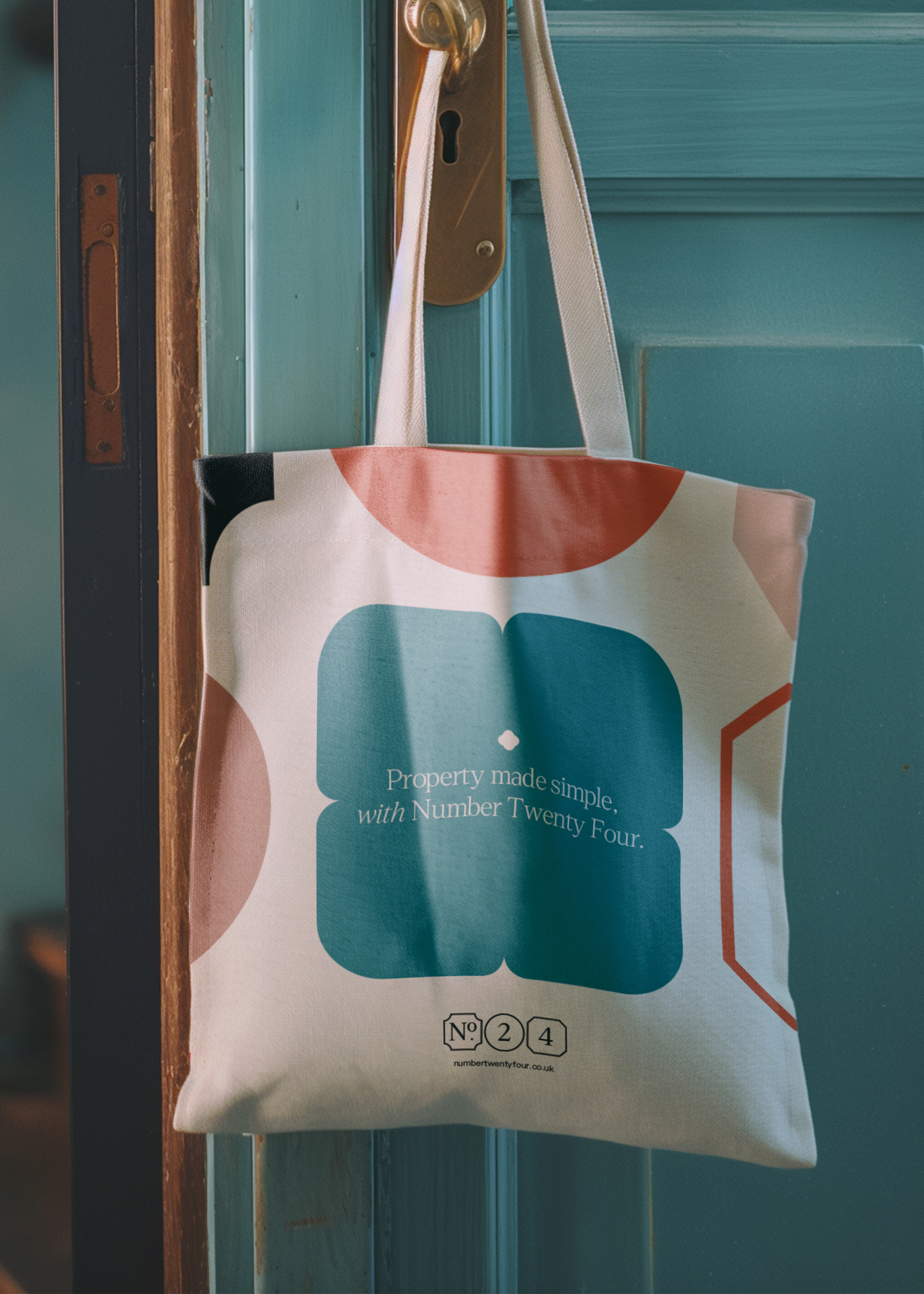 A tote bag haging on a door handle, with the brand strapline in a large brand shape, which in this case is a rounded edge square.