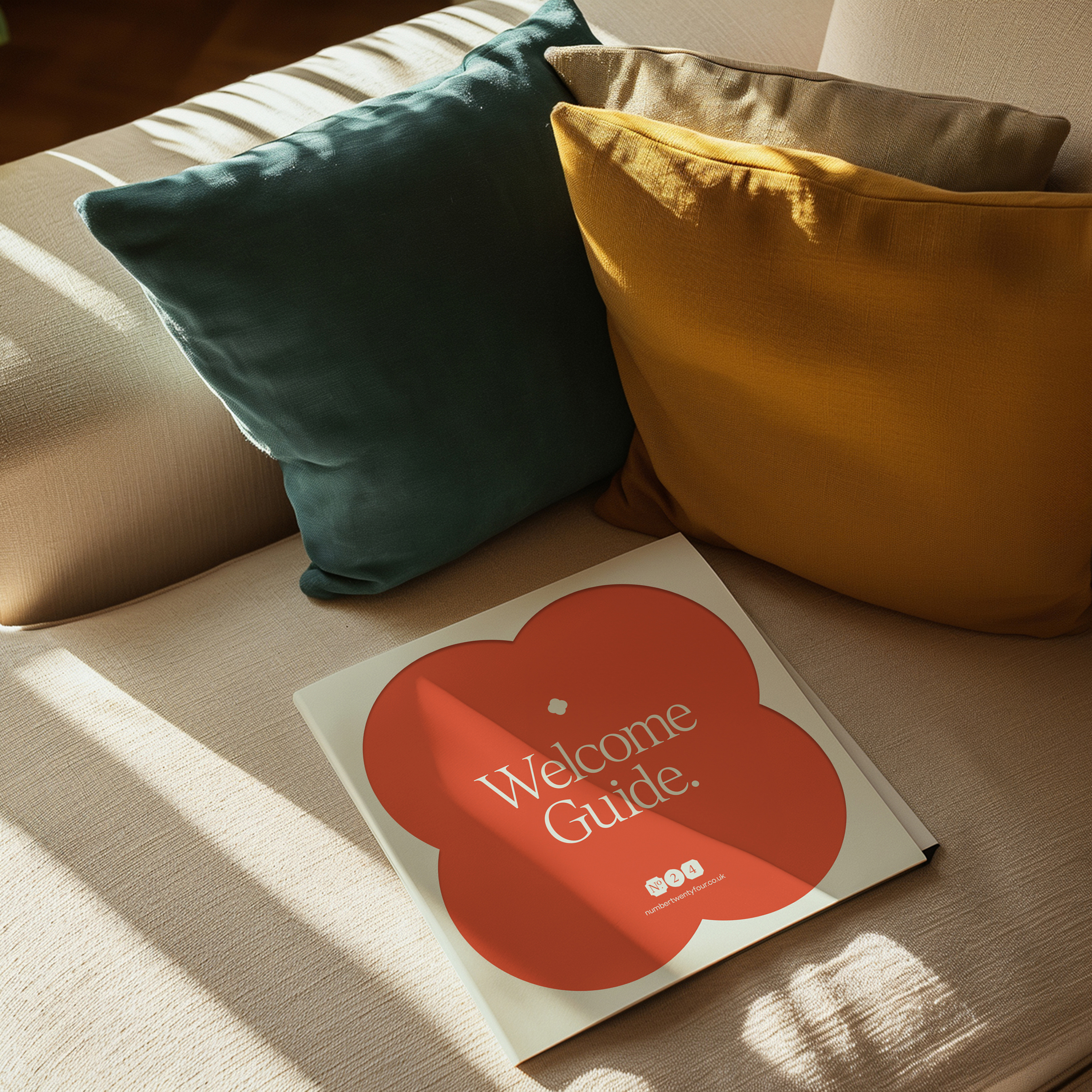 A square welcome guide booklet, laying on a cream sofa.