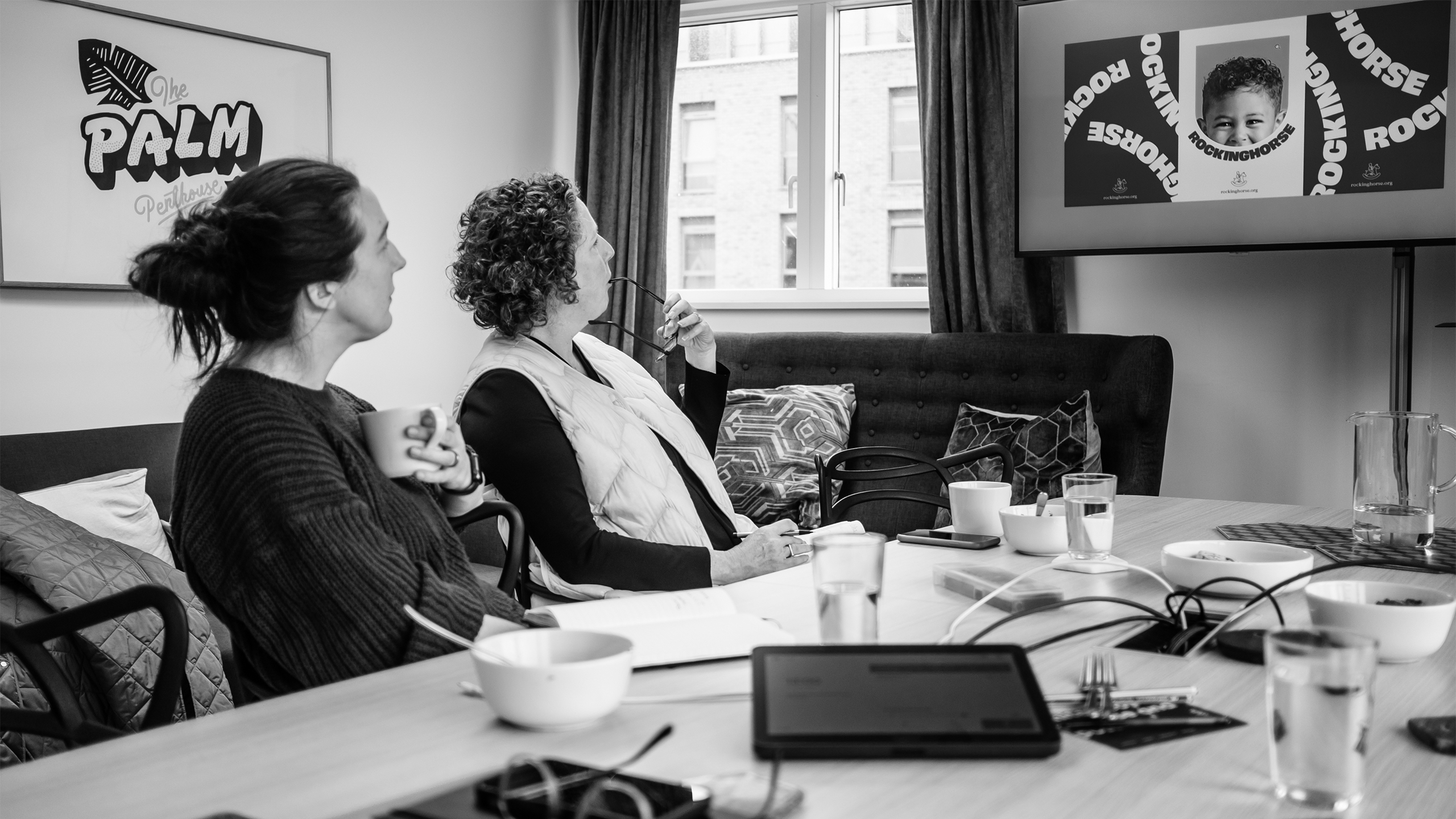 UnitedUs clients in a brand presentation where they are reviewing design work on a TV screen