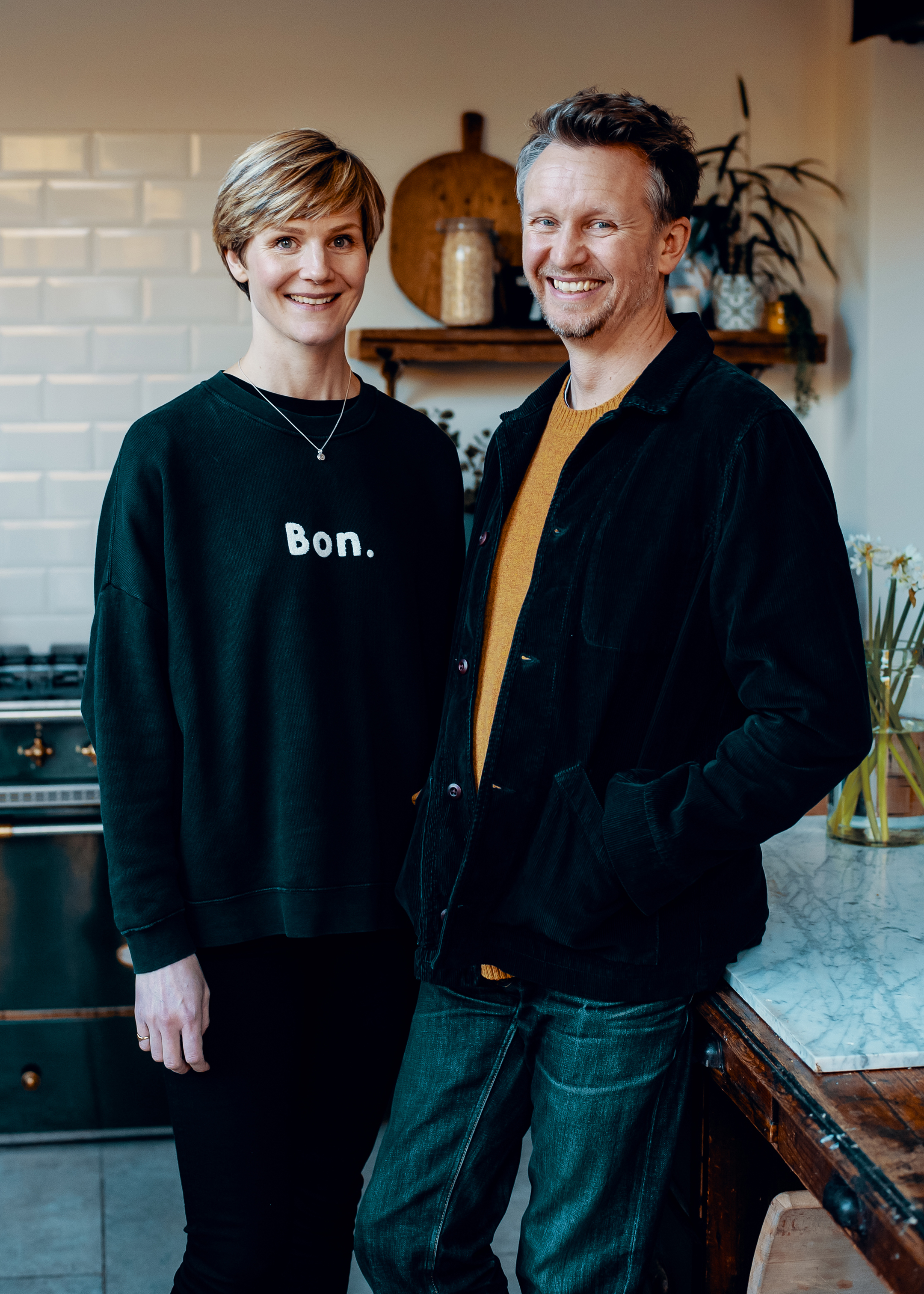 Portrait of Paul and Alex Clarke, wearing casual clothes in the kitchen of a country house.