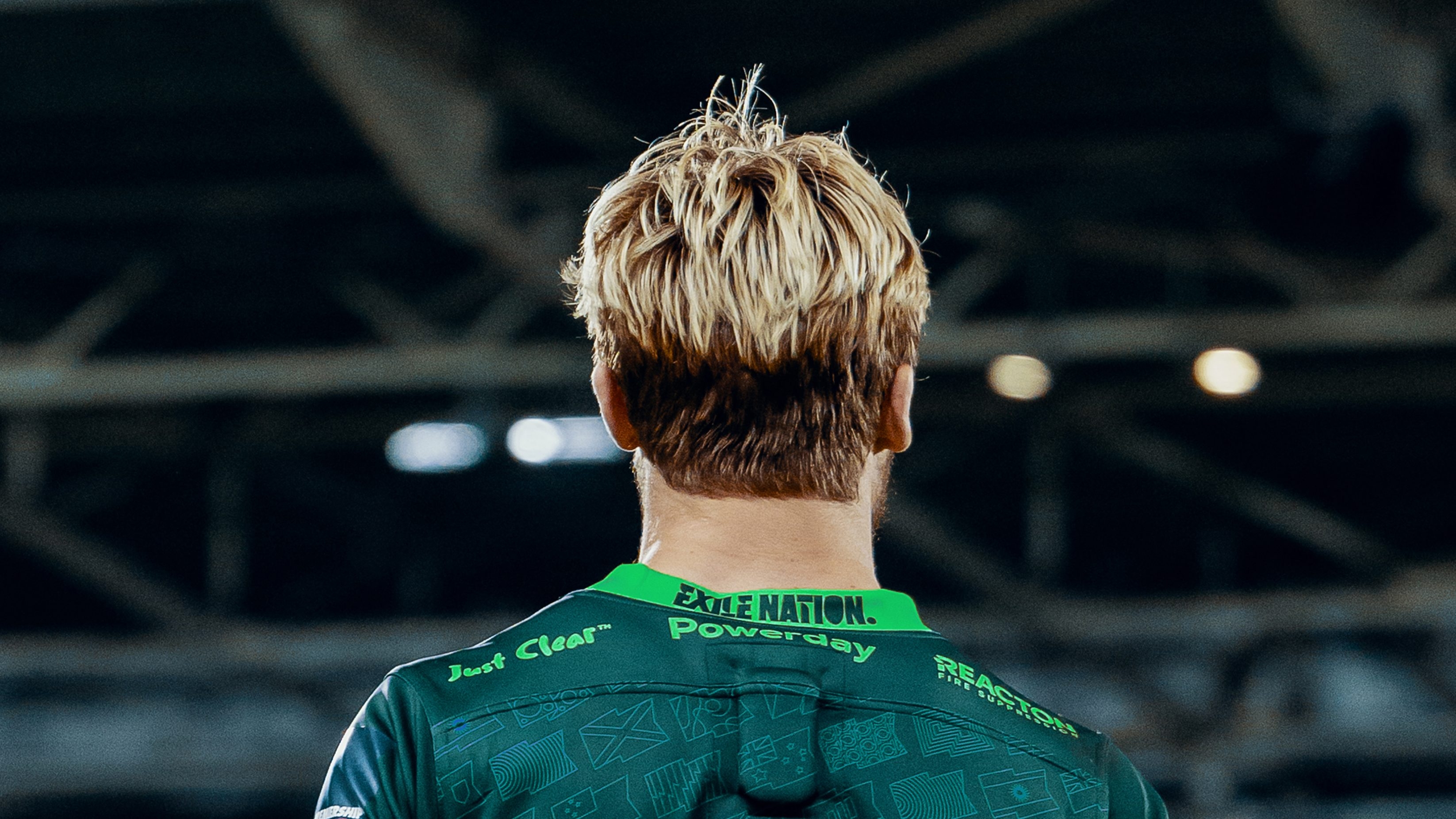 The back head and shoulders of a rugby player on the pitch wearing London Irish’s team kit