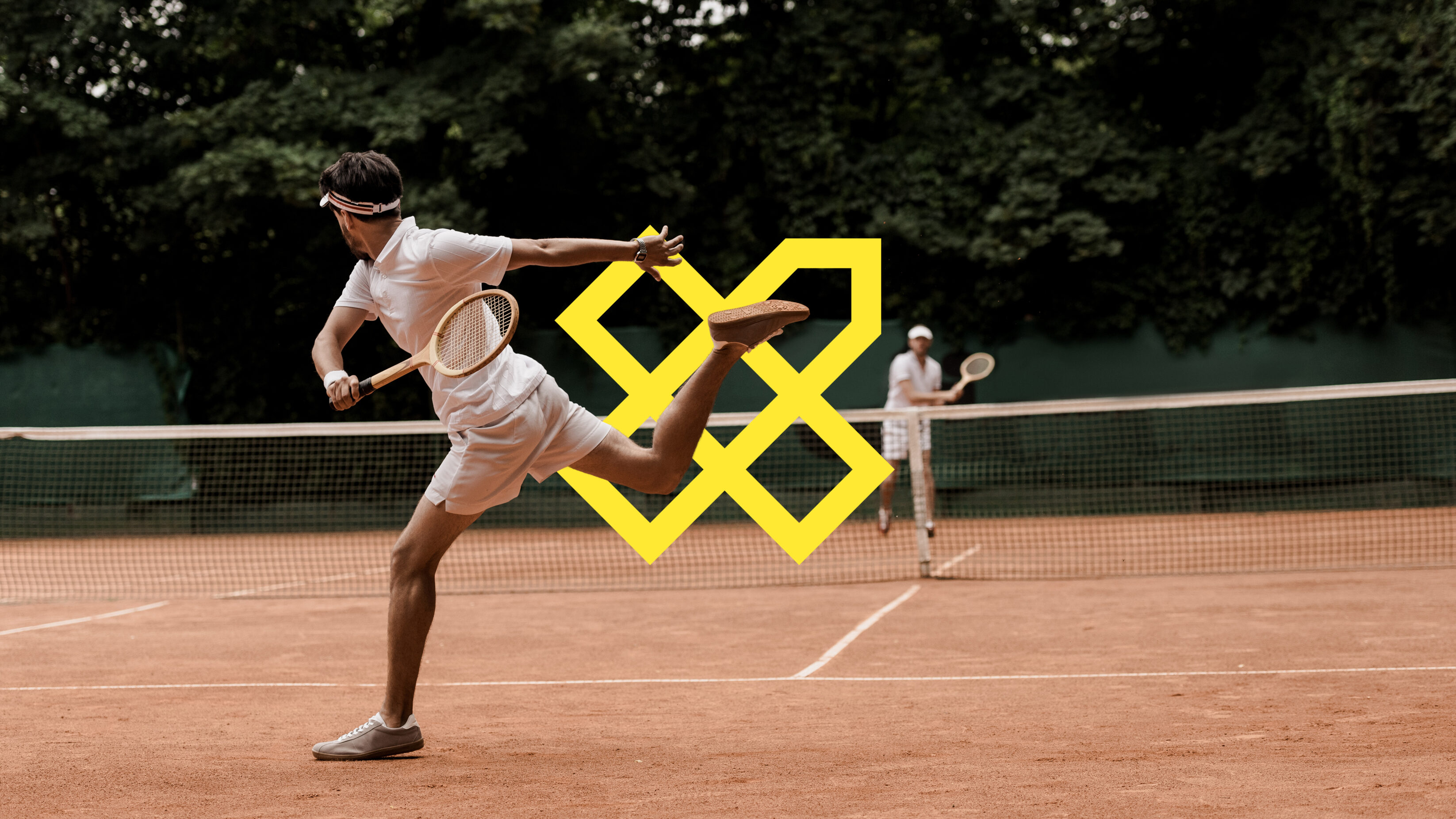 A vintage tennis match played on clay with wooden rackets. The player runs for the ball and the vox logo in outline is placed between him and the net.
