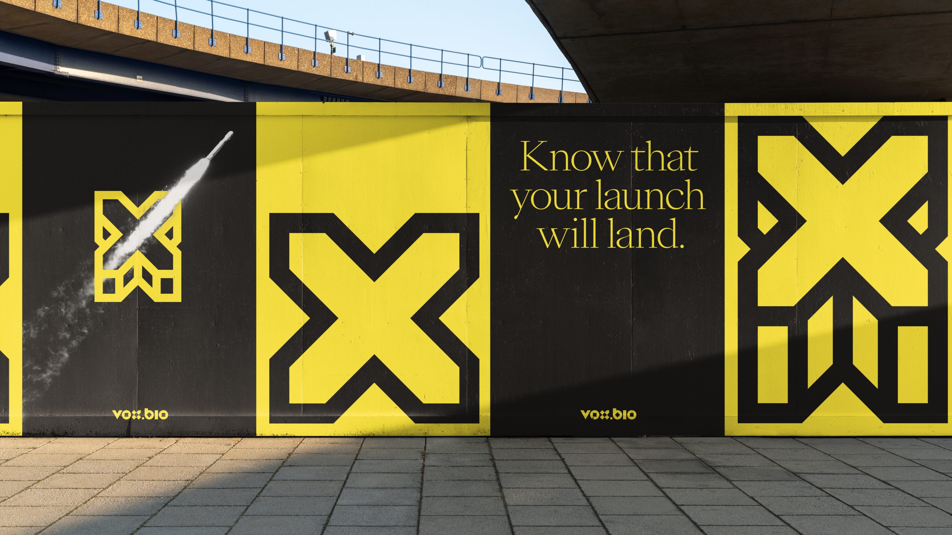 A large construction wall made of branded panels of yellow and black. There are various bold icons interspersed with Know that your launch will land