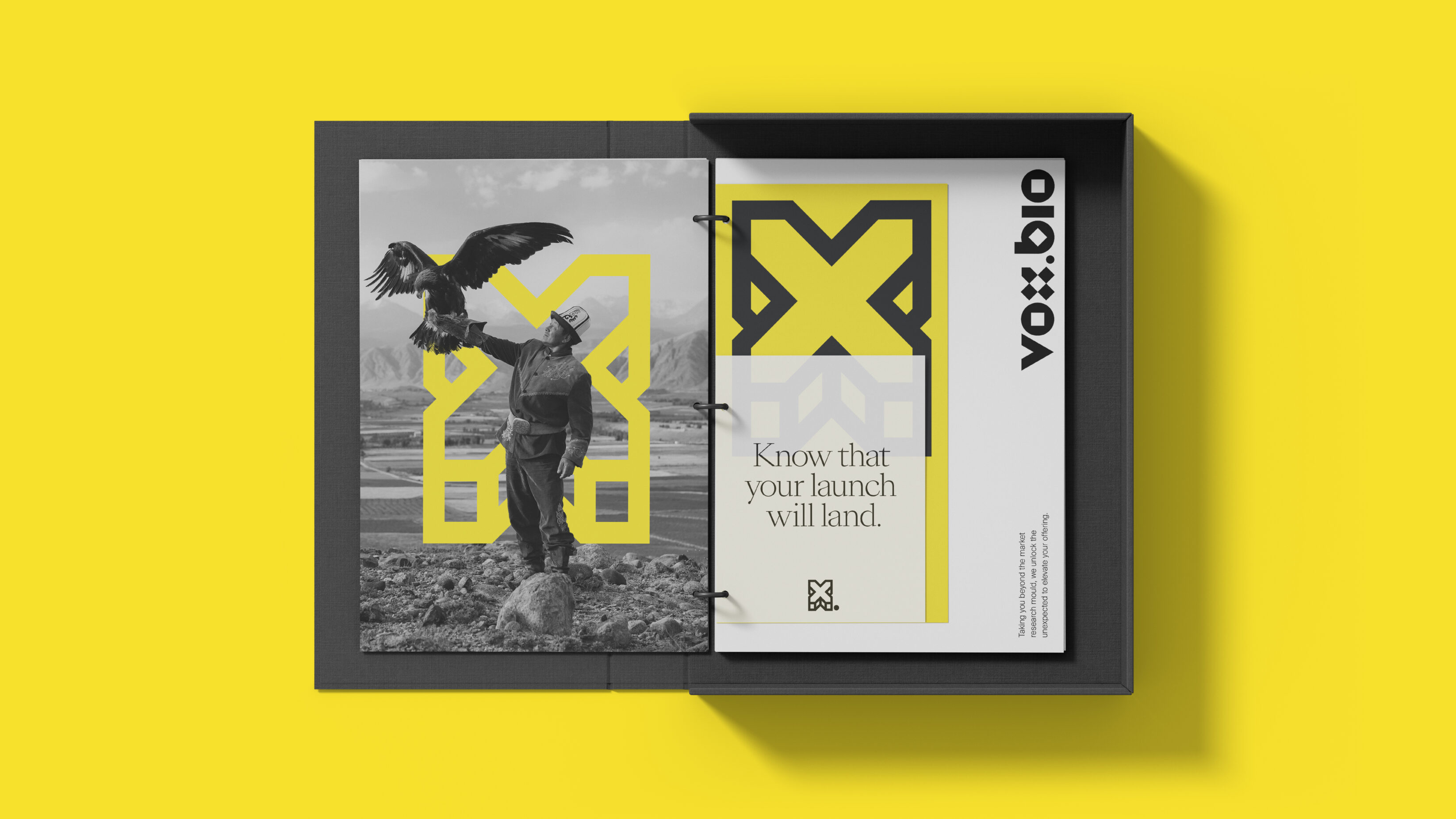 An open boxed binder. The left page is black and white and of a man holding an eagle about to take flight. On the right is a selection of Vox.Bio papers