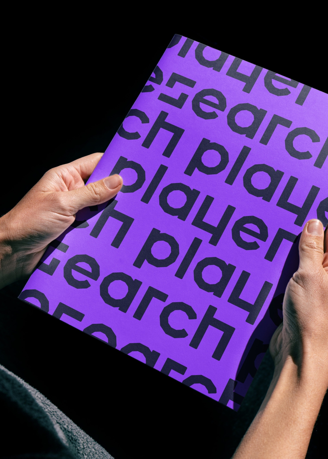 hands holding purple brochure with player research logo printed on it