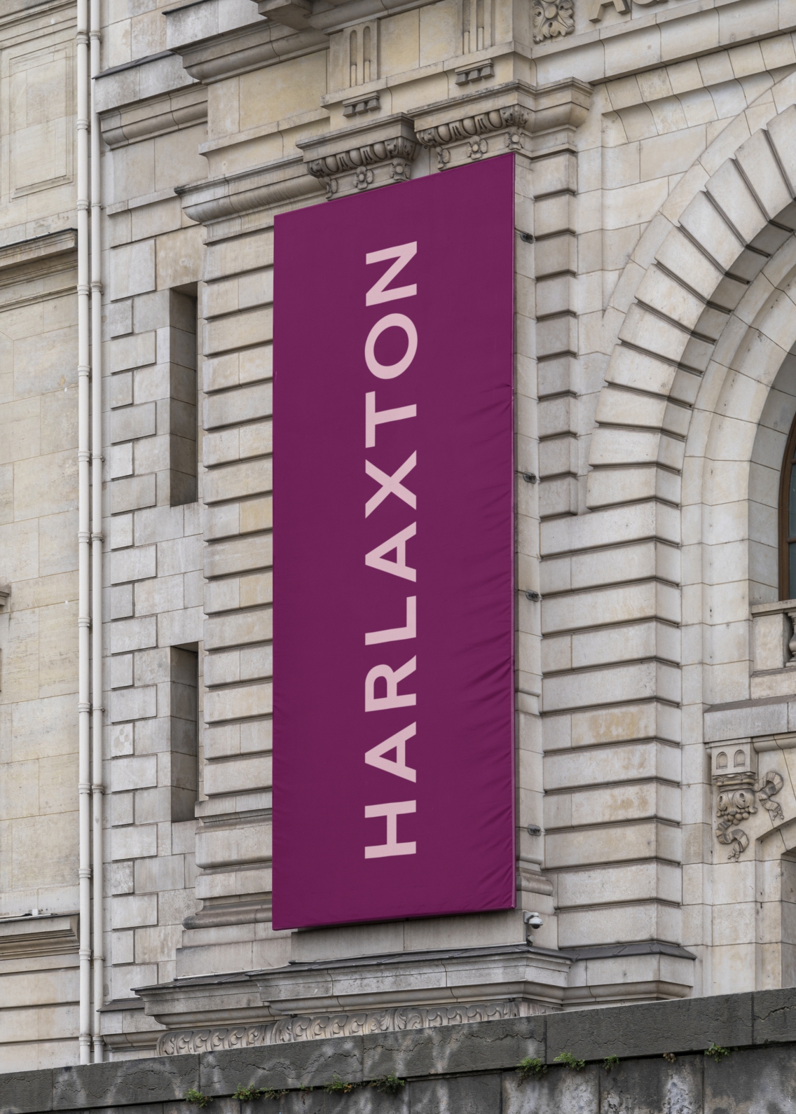 Maroon fabric banner hanging from the side of a building.