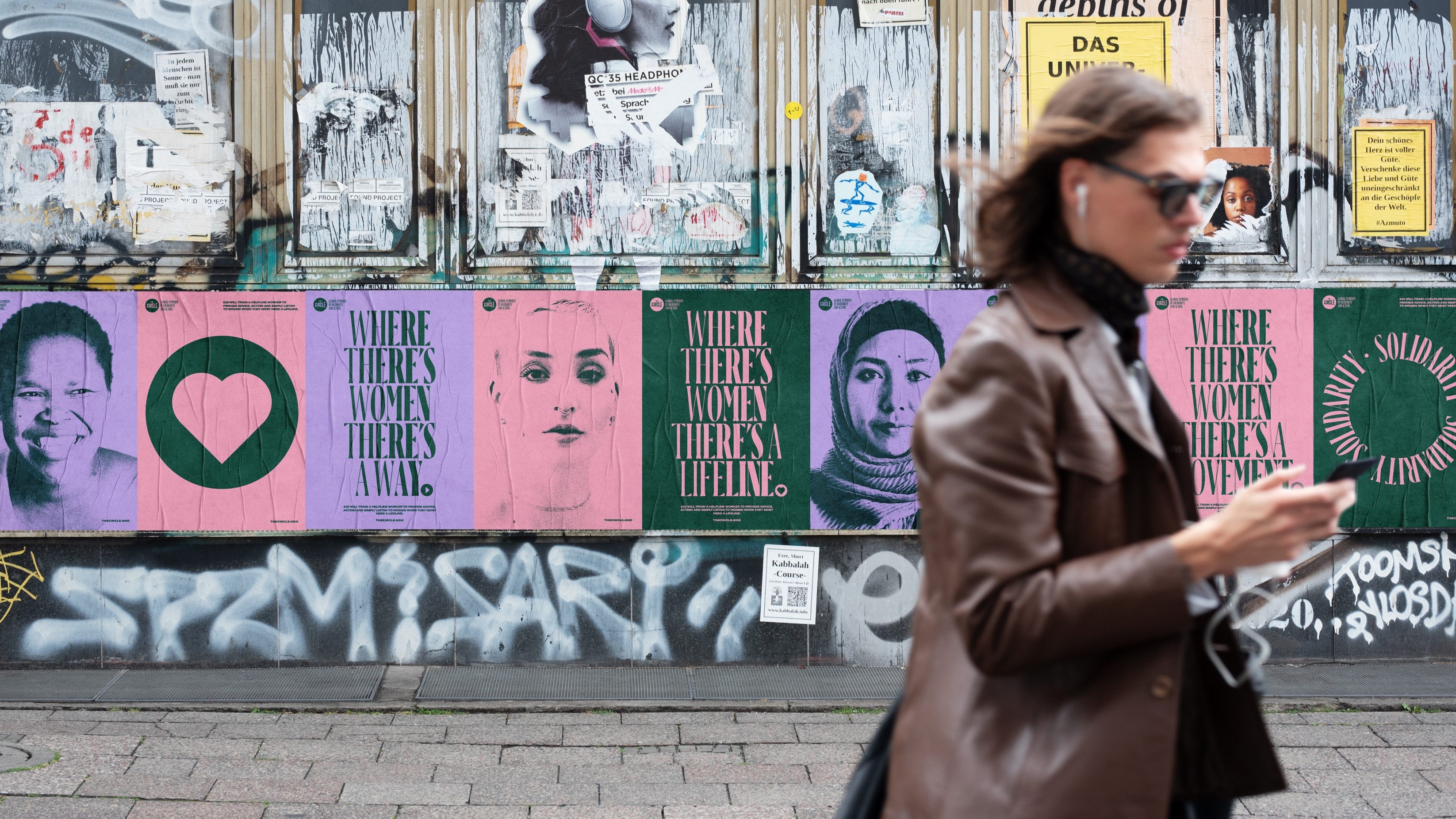 Posters on a run-down wall with messages of 'where there's women there's a way', 'where there's women there's a lifeline' and 'where there's women there's a movement' interspersed with portraits of a diverse range of women