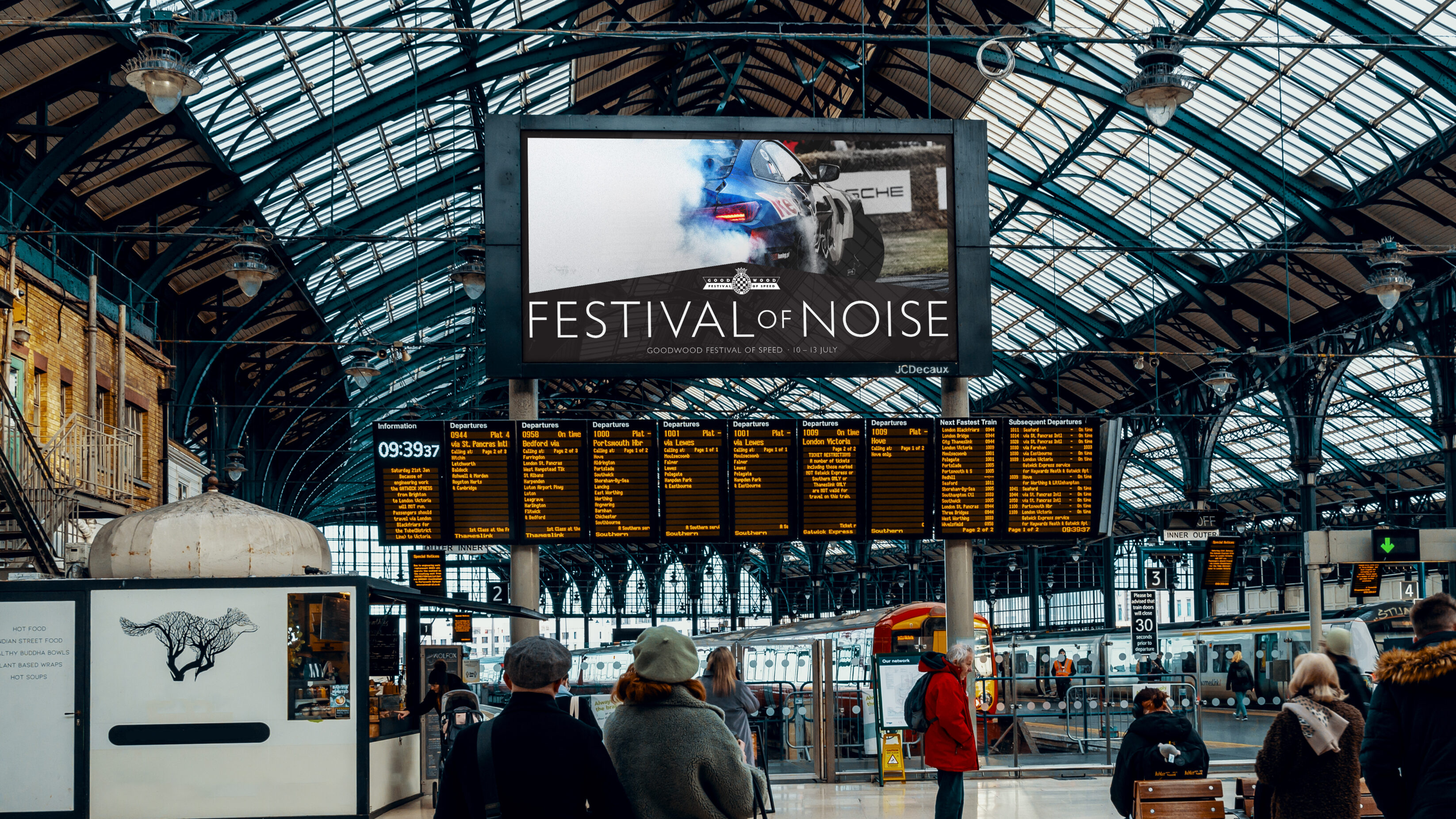 Digital billboard at Brighton station, showing an poster promoting the Festival of Noise theme.