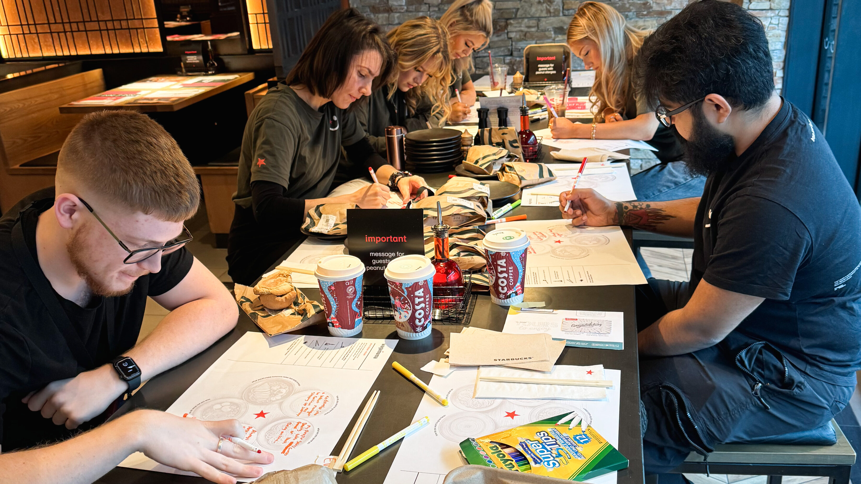 A team of wagamama employees in an employer brand workshop - lots of felt-tips and worksheets