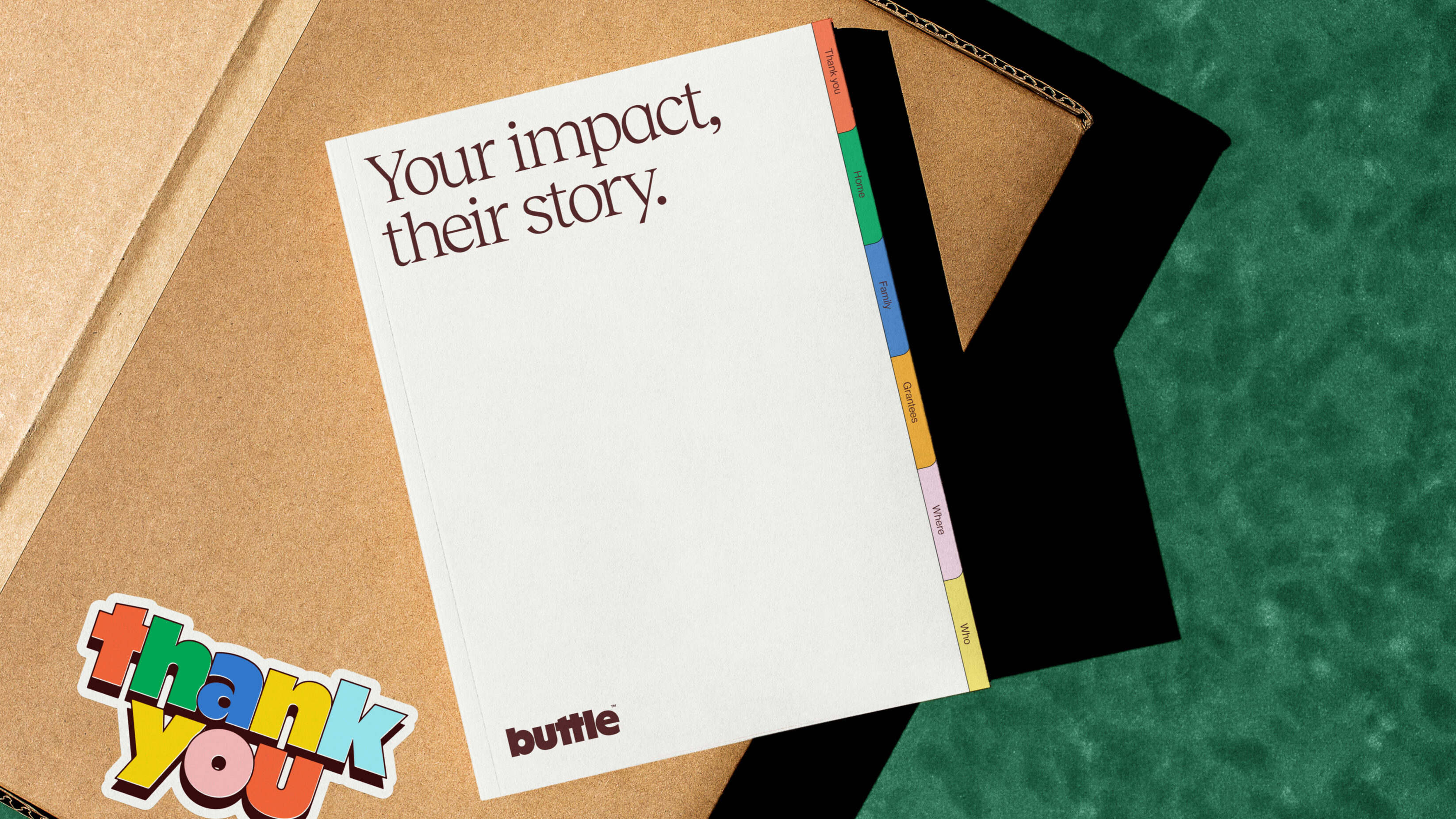 Impact report book, sat on a cardboard with, with a 'thank you' sticker on it.